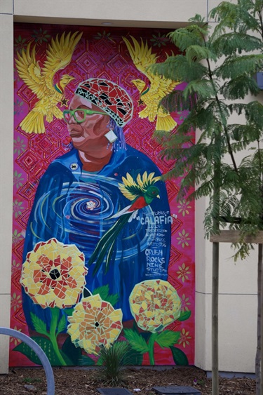 A colorful mural with mosaic elements painted on the wall of a building. 