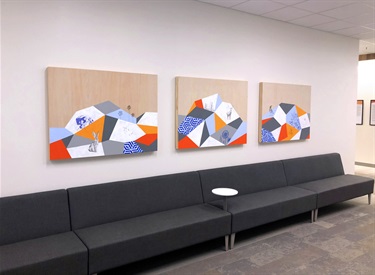 Three pieces of artwork hanging on a wall above a couch. 