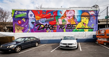 A colorful mural painted on a wall in a parking lot. 