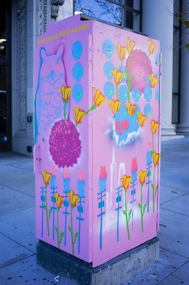 A painted utility box on a city sidewalk. 