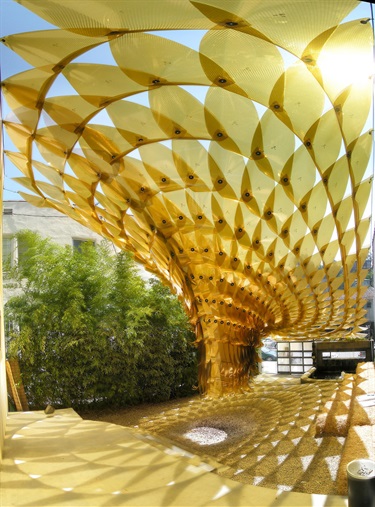 A yellow sculpture casting shadows on the ground. 
