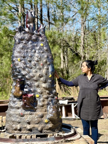 A person standing next to an abstract sculpture. 