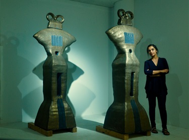 A person standing next to abstract sculptures. 