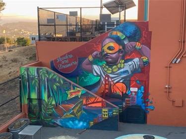 A colorful mural on the side of a building and staircase wall. 