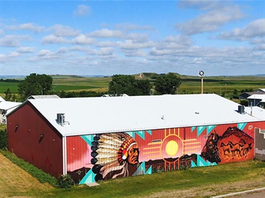 A colorful mural on the side of a red barn. 