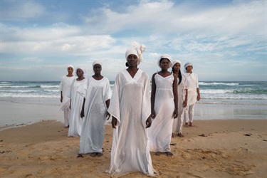A photograph of people standing on a beach.