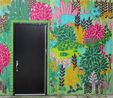 A colorful mural on a wall with a black door. 