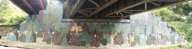 A painting on a wall underneath a bridge. 