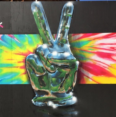 A painting of a metallic hand holding up a peace sign.
