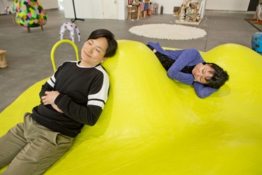 Two people sitting on a yellow structure.