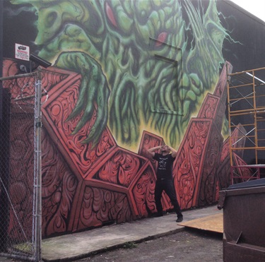 A person standing in front of a mural painted on the side of a building.