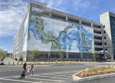 Large green and blue artwork on the side of a parking lot. 