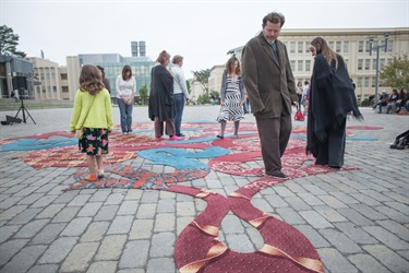 People walking around a ground art installation. 
