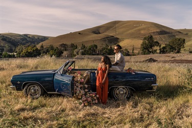 Two people standing near a car. 