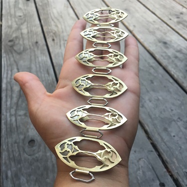 A hand holding a piece of metal jewelry.