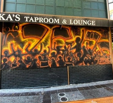 Mural on the outside of a building near the sidewalk. 