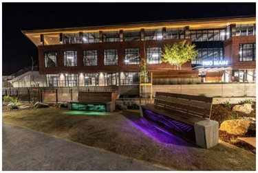 A building in a night setting with benches lit from underneath with colors. 