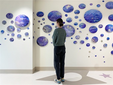 A person looking at an art installation on a white wall. 