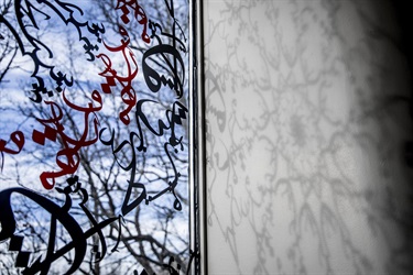 A design on a window casting shadows on a white wall. 