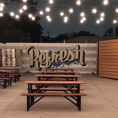 A mural with text on a wall and benches in the foreground. 