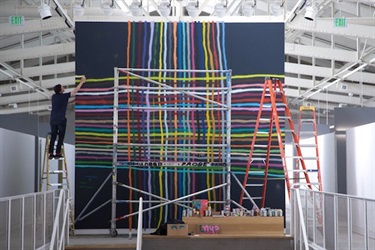 A person installing a large piece of artwork in a gallery. 