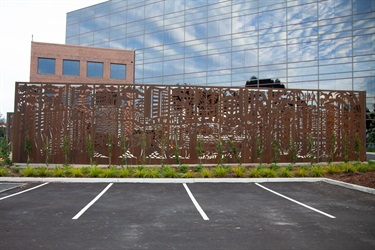 A metal decorated fence next to a parking lot. 