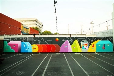 A mural painted on a wall near a parking lot. 