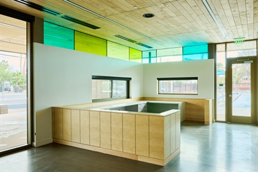 An empty room with a counter top and colored glass windows. 