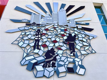 A laser cut art piece on the wall of a building. 