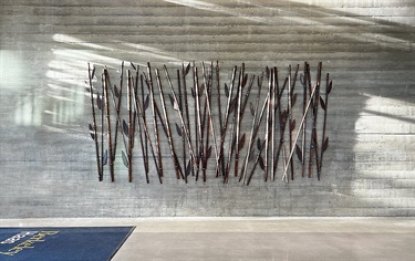 A sculpture of bamboo reeds on a wall.