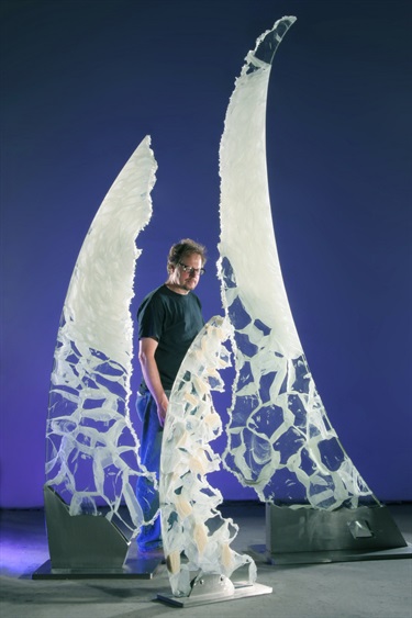 A person standing in between abstract glass sculptures.