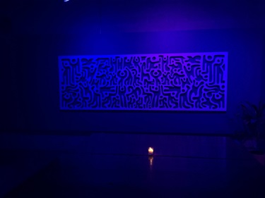 A blue-lit room with a piece of artwork on the wall. 