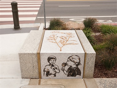 Artwork installed on a concrete block on the sidewalk. 