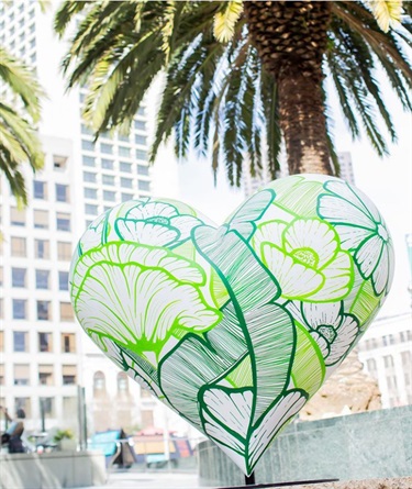 A heart shaped sculpture painted with artwork. 