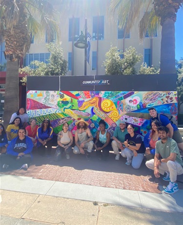 A group of people in front of a mural. 