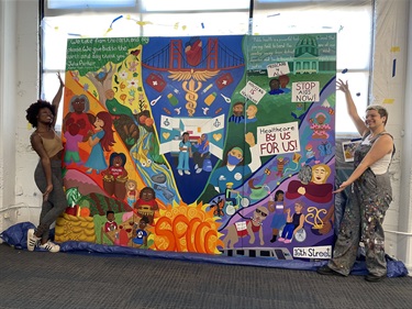 Two people standing next to a large painting.