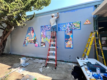 A person painting a mural on a building wall. 