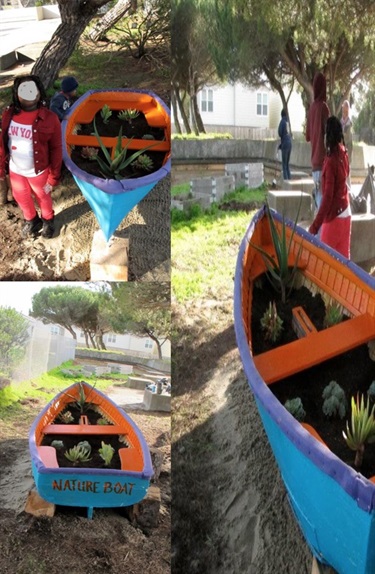A colorfully painted canoe with soil and plants inside. 