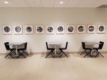 A white room with art on the wall, tables and chairs. 