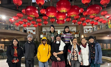 A group of people standing together. Red lanterns are above them. 