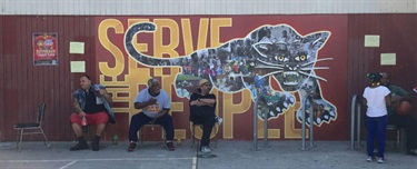People sitting in front of a mural.