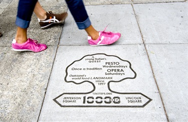 Feet walking past a tree-shaped marker in the concrete of the sidewalk.