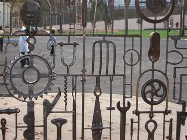 A detail of a steel gate incorporating found objects at the entrance of a community park.