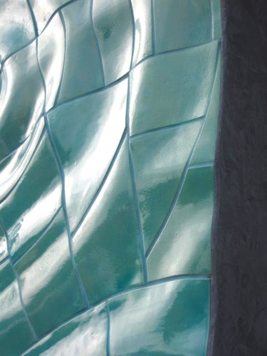 A a detail picture of a teal tile installation in front of the entrance of a pool. 