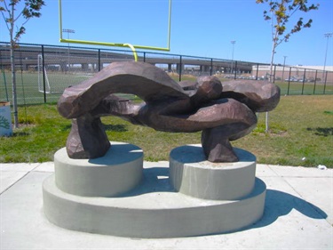 A bronze abstract sculpture on a concrete podium.