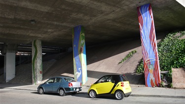 A mural painted podiums on the underside of an overpass.