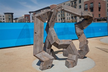 A sculpture with apartment buildings behind it. 