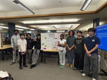 Oakland high students in front of a poster of their work