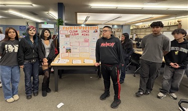 Oakland High students stading in front of a poster of their work