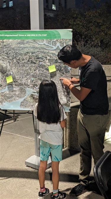 People sharing feedback via a map printout outside OMCA